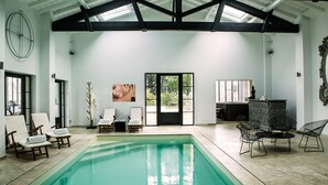 A spacious indoor pool area with a large pool, lounge chairs, and a modern interior design. - Chateau du Palanquey & SPA (Sainte-Colombe)