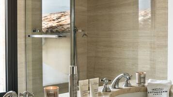 A modern bathroom with a large mirror, two sinks, and a shower.
