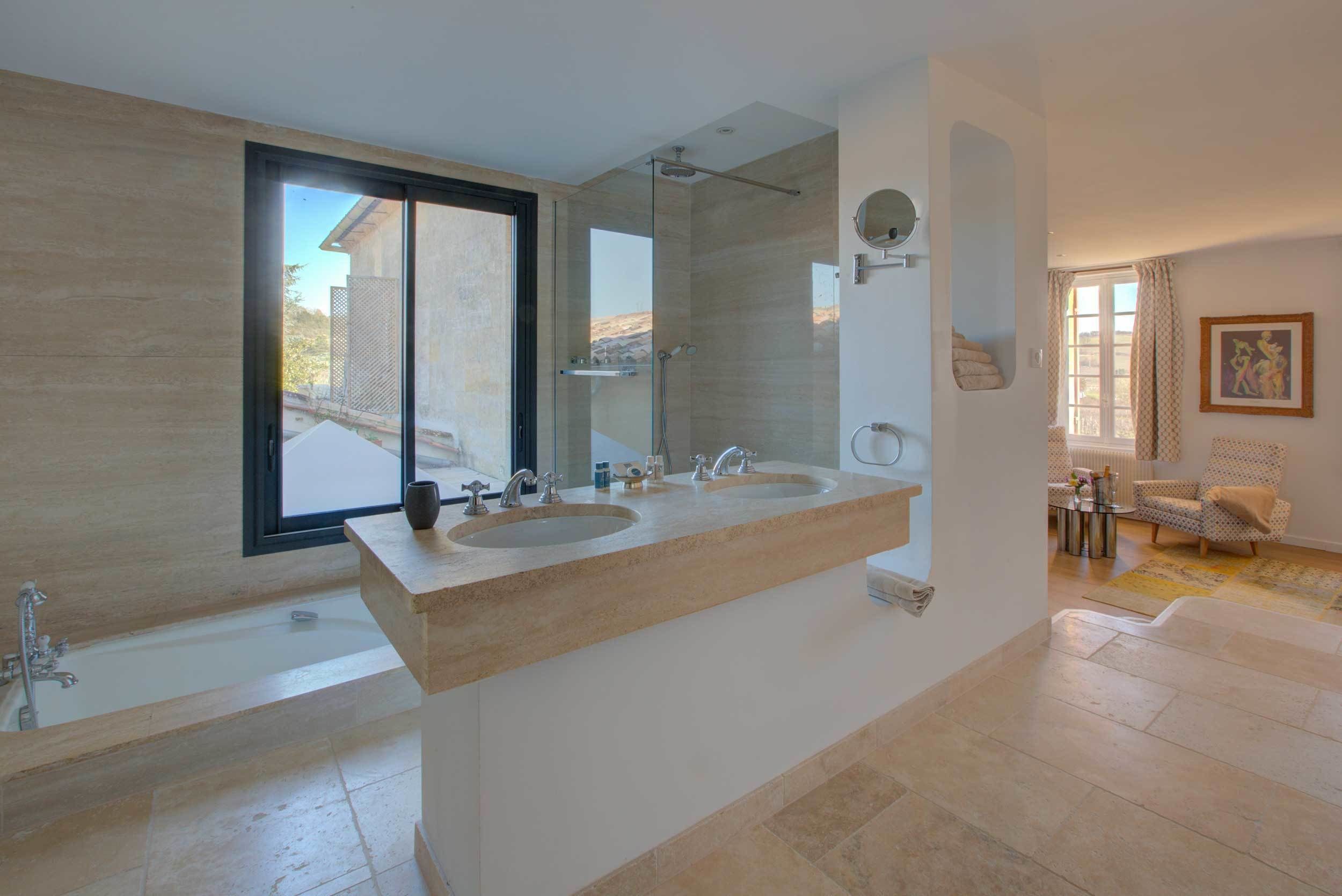 A modern bathroom with two sinks, a bathtub, and a large mirror.