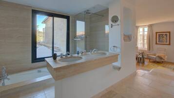 A modern bathroom with two sinks, a bathtub, and a large mirror.