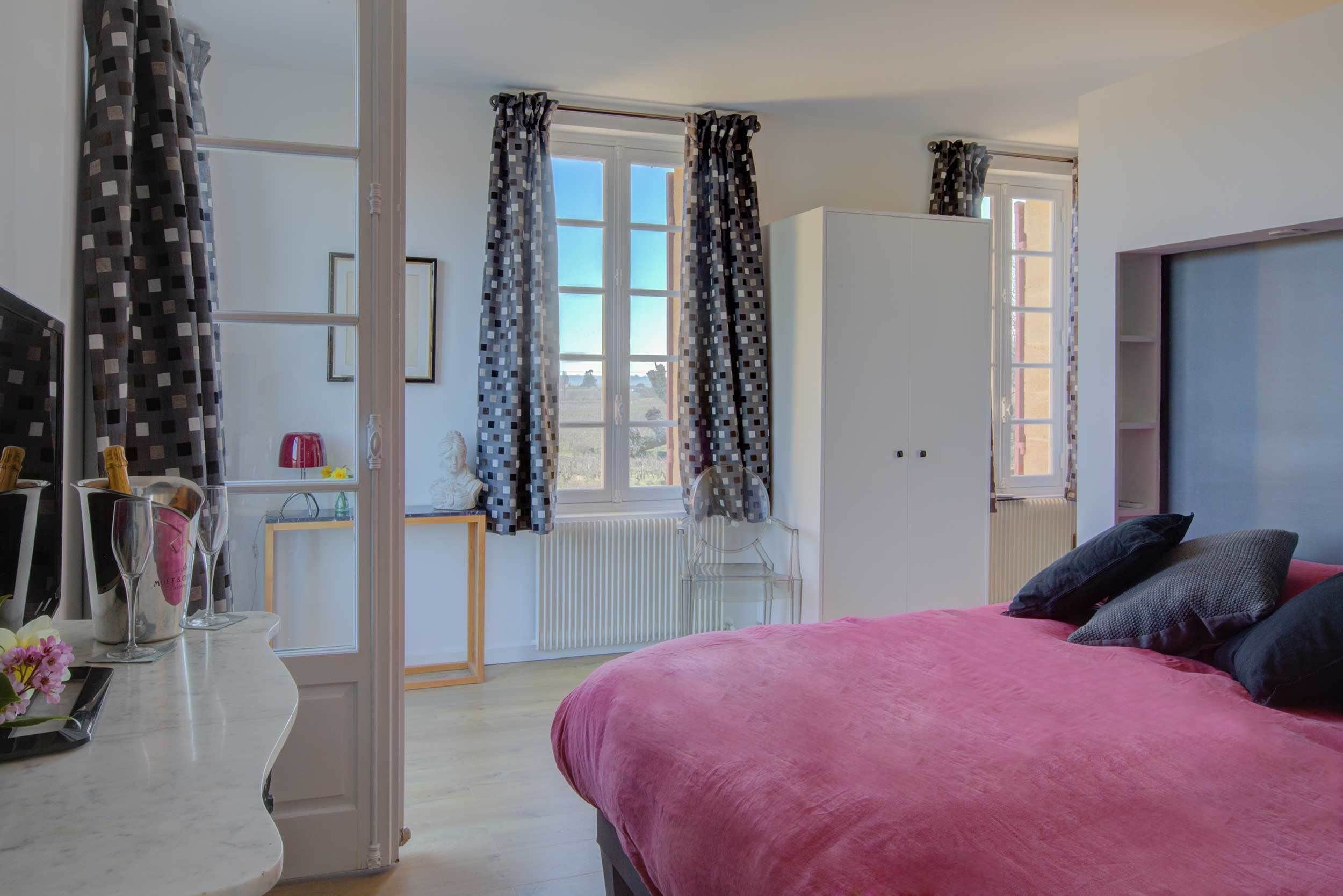 Un dormitorio con cama, cómoda, ventana con cortinas y radiador.