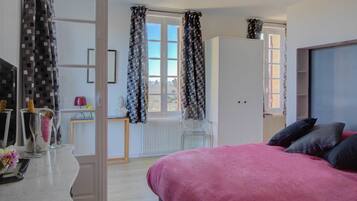 Un dormitorio con cama, cómoda, ventana con cortinas y radiador.