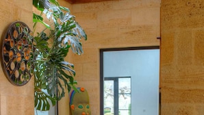 A modern interior with a large plant, a colorful sculpture, and a view to the outside. - Chateau du Palanquey & SPA (Sainte-Colombe)
