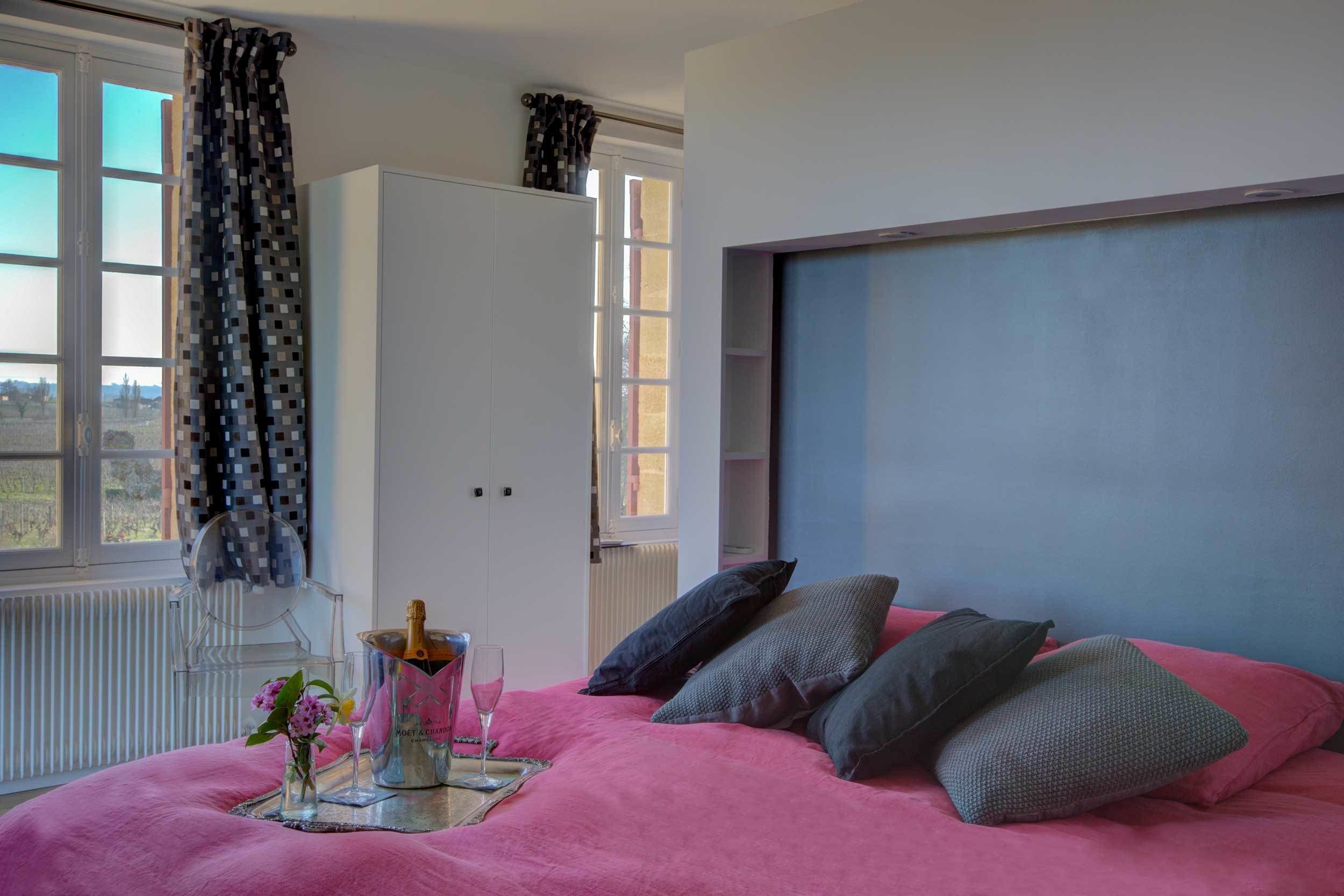 Un dormitorio con una cama grande, una mesita de noche con una botella y un vaso, y una ventana con cortinas.
