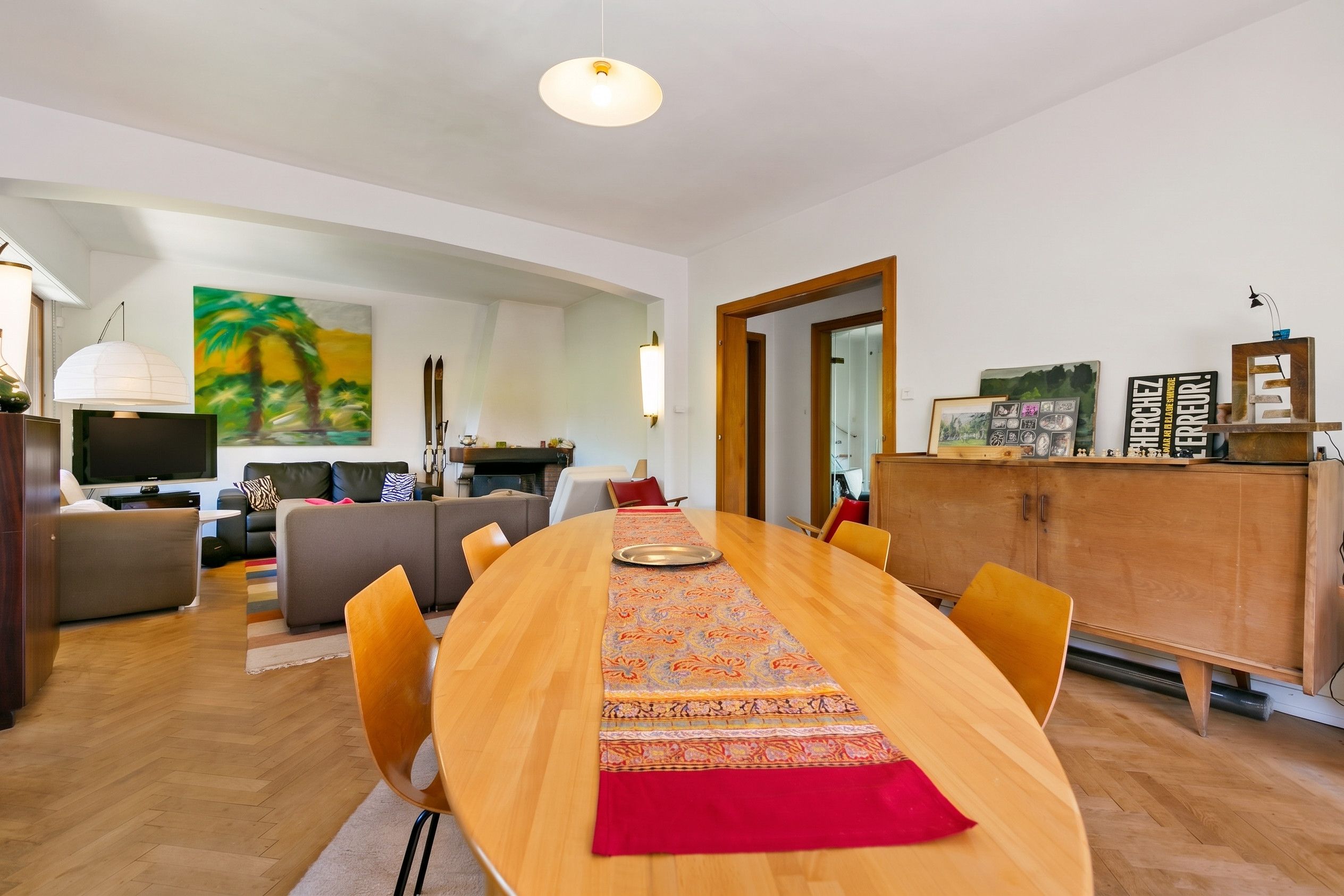 Una sala moderna con una mesa de comedor de madera, sofás y un televisor.