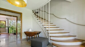 A modern interior with a spiral staircase, a wooden bench, and a small ottoman.