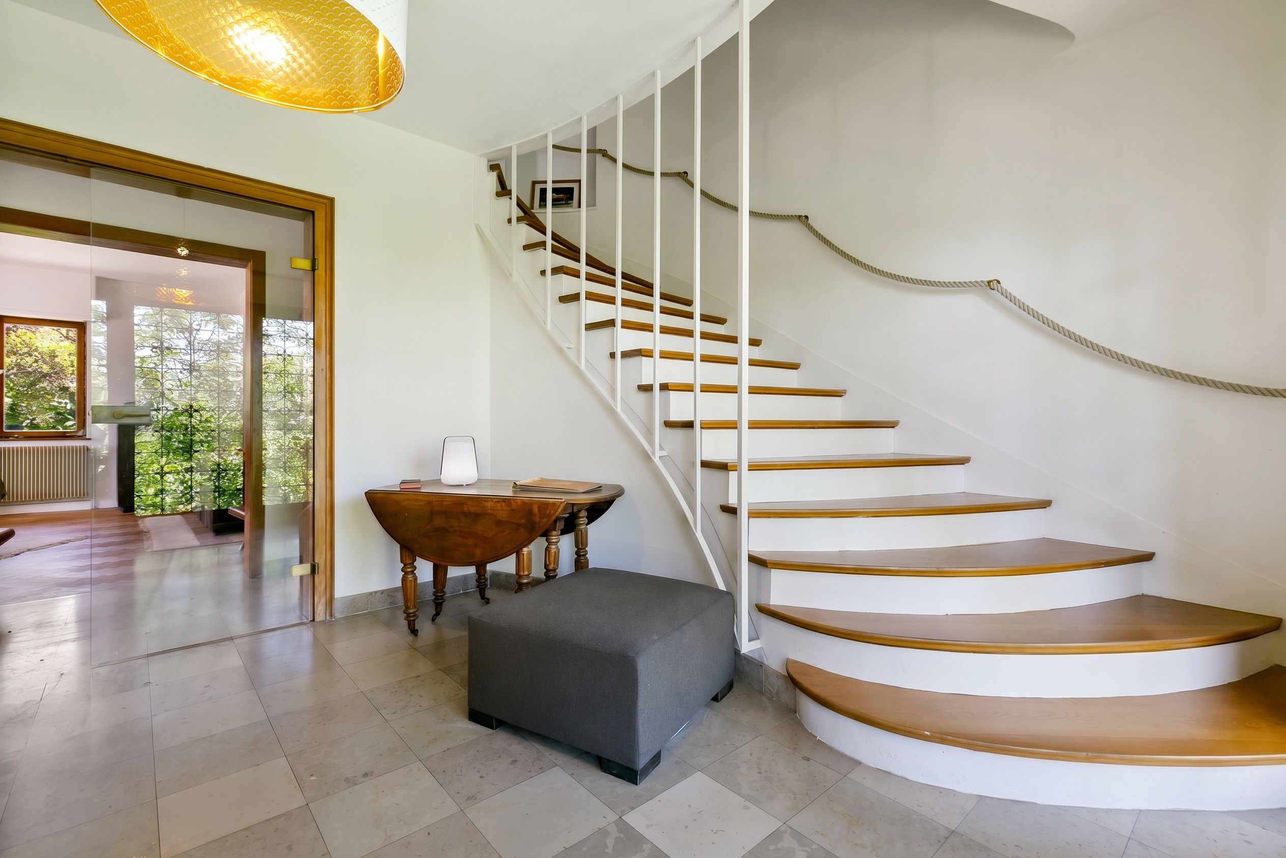 Ein modernes Interieur mit einer Wendeltreppe, einem runden Tisch und einer Bank.