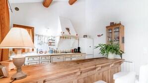 A kitchen with a wooden bar counter, white cabinets, and a potted plant. - Gorgeous home in Pernes les Fontaines (Pernes les Fontaines)
