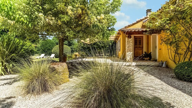 A house with a yellow facade, a stone entrance, and a garden with white chairs and tall grasses. - Gorgeous home in Pernes les Fontaines (Pernes les Fontaines)