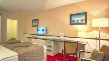Habitación de hotel con dos camas, un escritorio con computadora, una silla y un televisor.