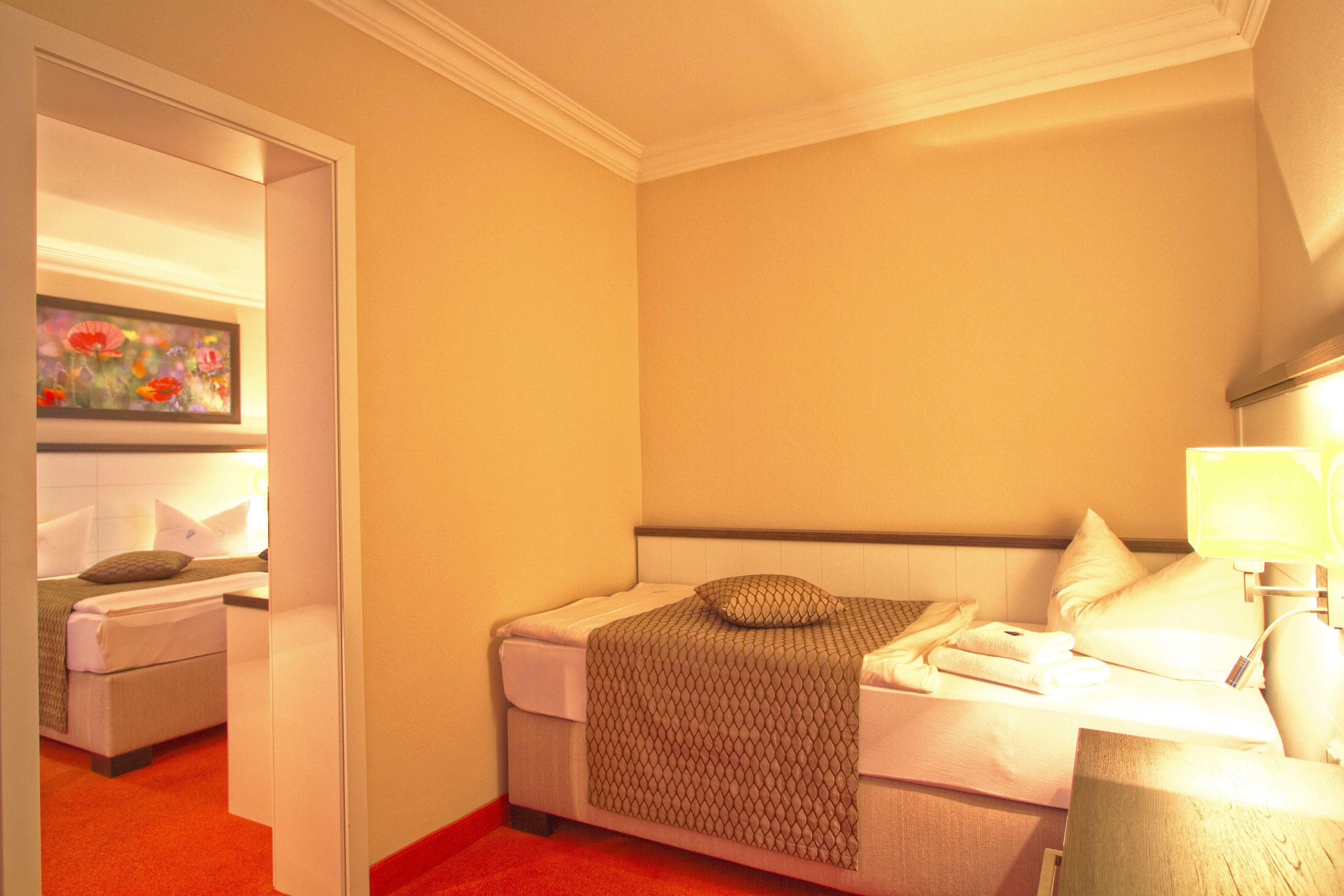 Ein Hotelzimmer mit Bett, Nachttisch, Lampe und einem Bild an der Wand.