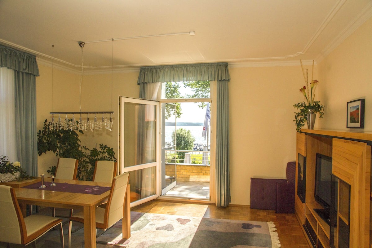 Ein Essbereich mit Tisch und Stühlen, einem Fernseher und einem Balkon mit Blick.