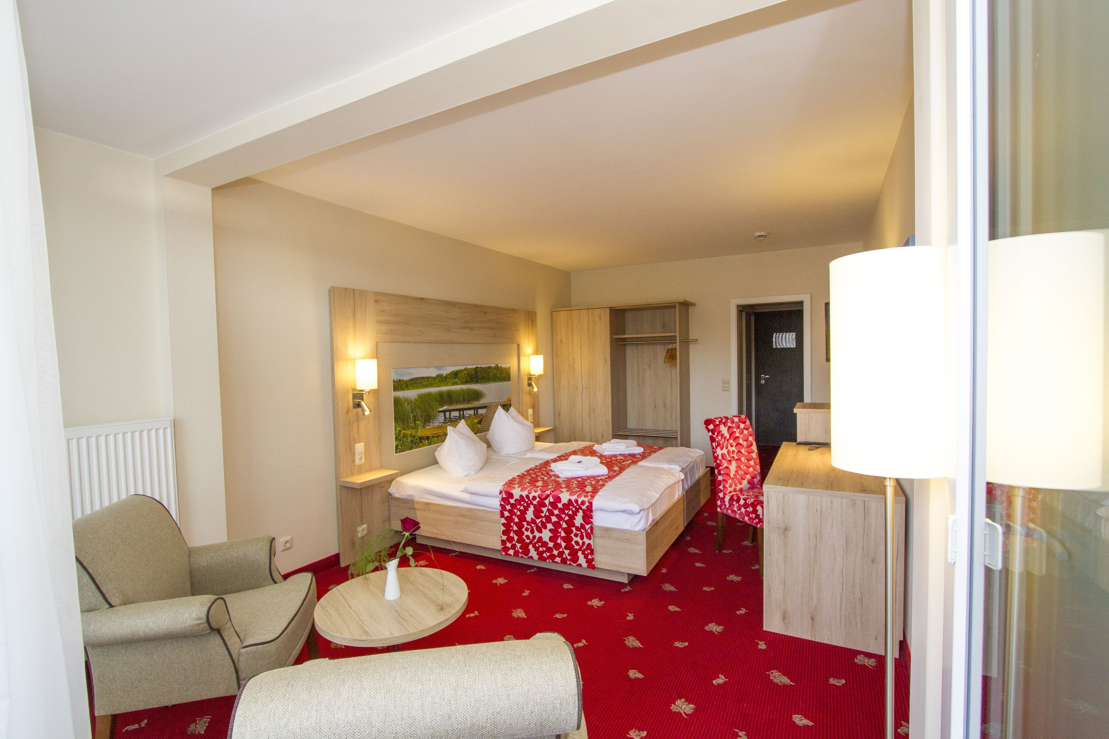 Een hotelkamer met een bed, een stoel, een klein tafeltje en een lamp.
