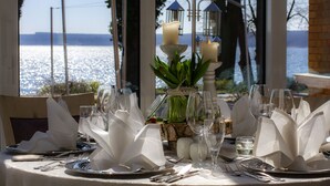A table set for a meal with candles, a vase with green plants, and a view of the sea. - Seehotel Plau Am See (Plau am See)