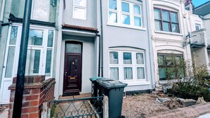 A two-story residential building with a dark brown front door, white-framed windows, and a satellite dish on the left. - TopHome Finsbury Park (London)