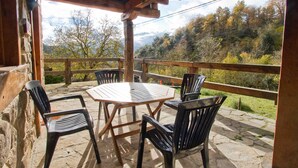 Una terraza de madera con una mesa y sillas, con vistas a un paisaje montañoso.