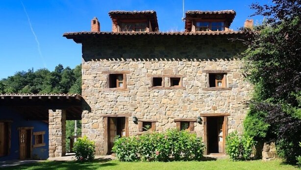 Un edificio de piedra con diseño rústico, que cuenta con varias ventanas y un césped bien cuidado.