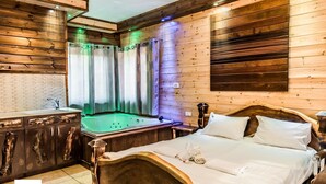Um quarto estilo cabana de madeira com uma cama, uma cabeceira de madeira, uma toucador de madeira com uma pia e uma banheira.