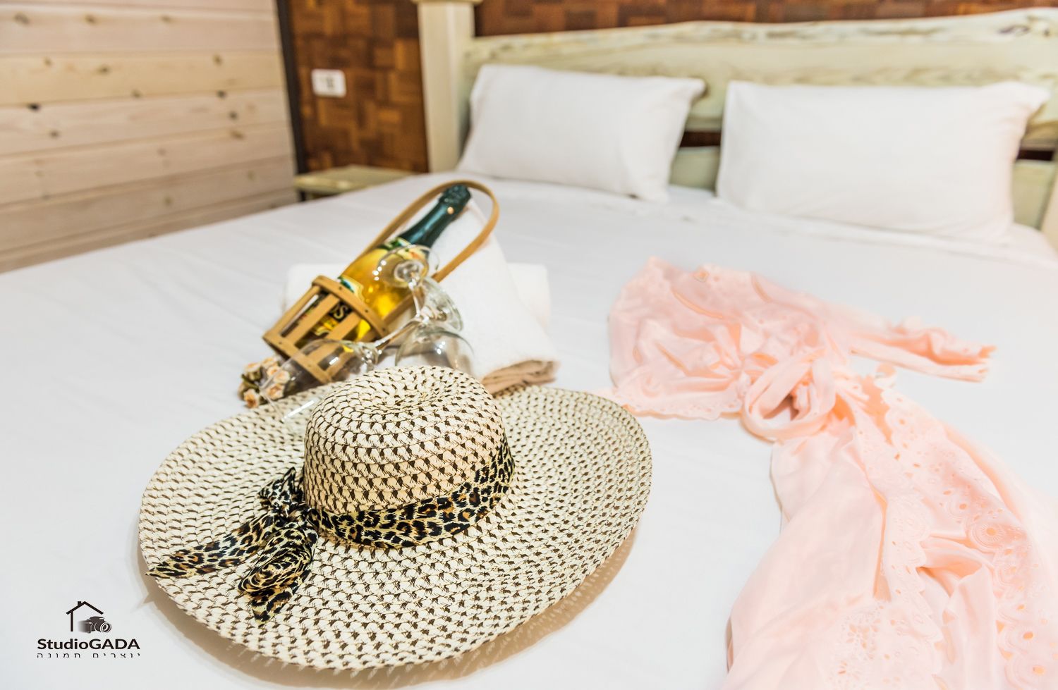 A bed with a straw hat, a champagne bottle, and a pink cloth.