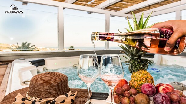 Área de hidromassagem com champanhe sendo servido, um chapéu, taças de vinho e um prato de frutas.