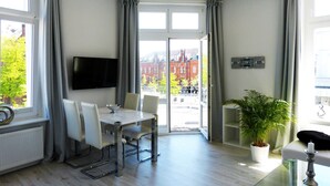 Ein modernes Wohnzimmer mit Essbereich, großen Fenstern und einer Topfpflanze.