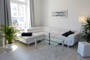 Una sala de estar moderna con un sofá seccional blanco, una mesa de centro de vidrio y una planta en maceta.