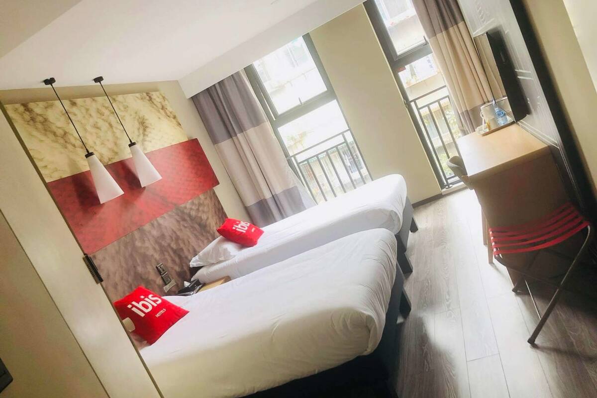 Une chambre d’hôtel avec deux lits, un bureau et un balcon.