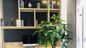 Espaço de trabalho moderno com escrivaninha, computador e planta em vaso.