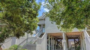A two-story building with a covered entrance and a staircase leading to the upper floor. - Sweet Serenity | Oceanfront Townhouse! (Topsail Beach)