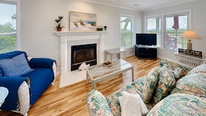 A living room with a fireplace, a television, a coffee table, and a sofa. - Sweet Serenity | Oceanfront Townhouse! (Topsail Beach)