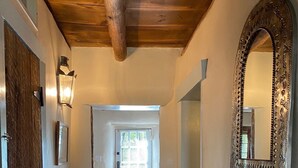 A hallway with a wooden door, a mirror, and a red mat leading to a room with a door. - Balloon Fiesta close to Charming, Historic, N. Valley Casita! (Albuquerque)