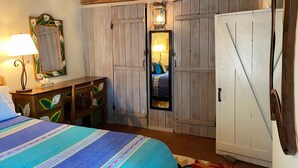 A bedroom with a bed, dresser, mirror, and wardrobe. - Balloon Fiesta close to Charming, Historic, N. Valley Casita! (Albuquerque)