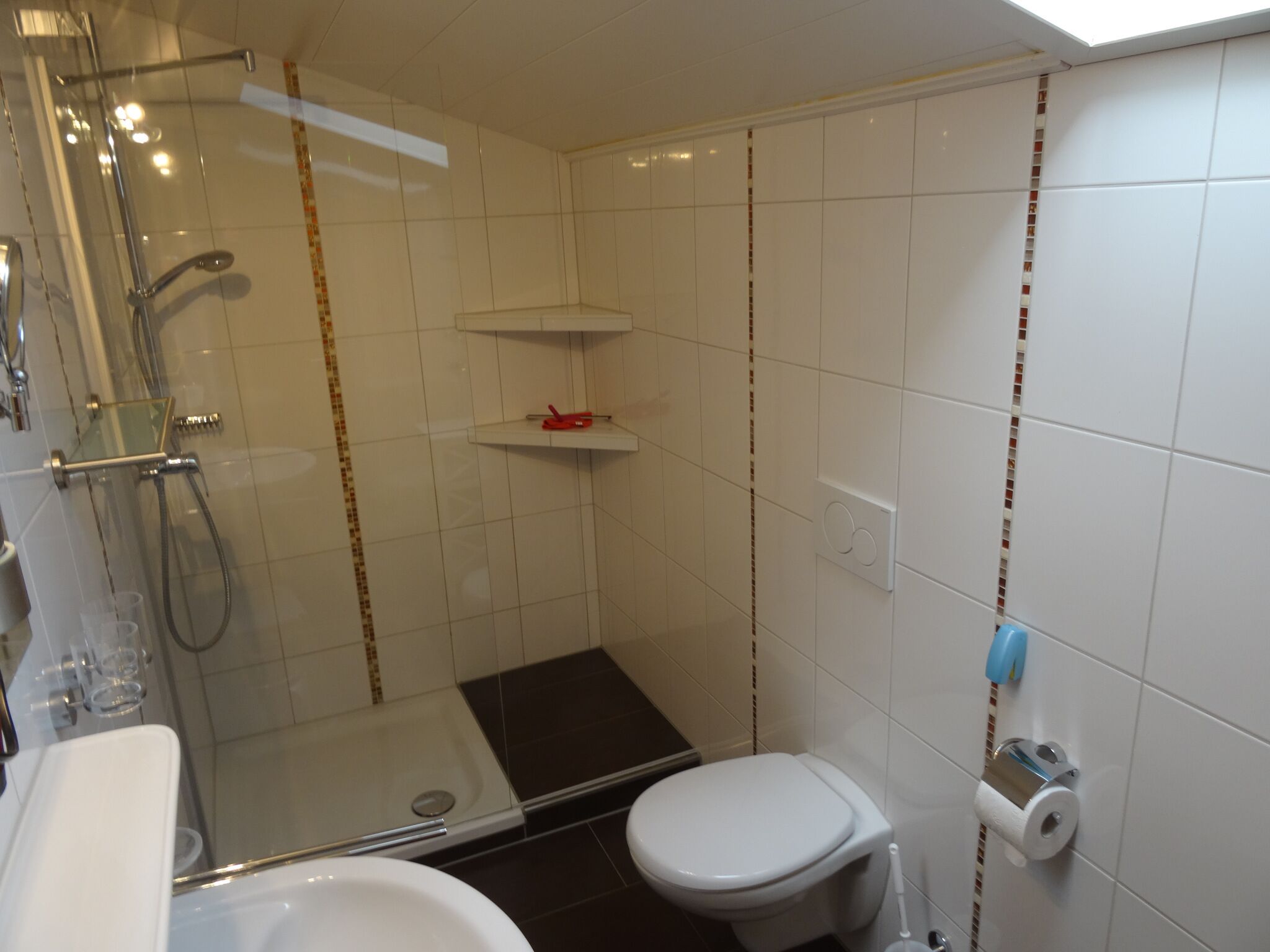 Ein kleines, modernes Badezimmer mit Duschkabine, Toilette und Waschbecken.