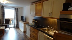 A compact kitchen with wooden cabinets, a built-in oven, and a coffee maker. - Apartment Anna for 4 persons, 2 bedrooms, kitchenette, bathroom, 72 sqm (Inzell)