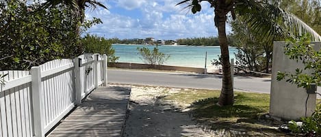 A wooden walkway leading to a beach with a view of the ocean and palm trees.