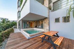 Uma área de piscina ao ar livre moderna com deck de madeira e mesa de piquenique.