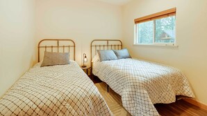 A small bedroom with two beds, a window, and a nightstand with a lamp. - Fisherman’s Cabin in Soldotna Near Kenai River! (Soldotna)