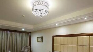 A hotel room with two beds, a chandelier, a chair, and a patterned carpet. - Jinou Hotel (Wenzhou)