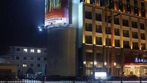 A hotel with a prominent illuminated sign on the facade, multiple floors, and a gated entrance. - Jinou Hotel (Wenzhou)