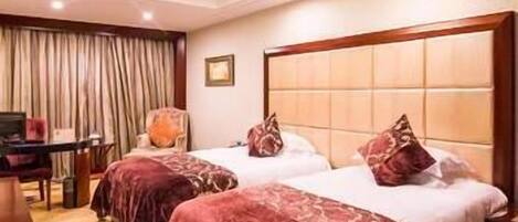 A hotel room with two beds, a desk, and a chair.