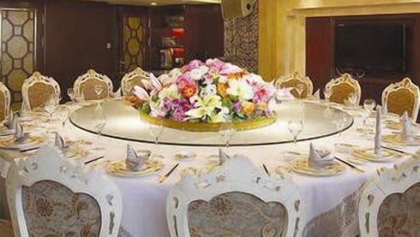 A round dining table with a floral centerpiece, surrounded by ornate chairs. - Jinou Hotel (Wenzhou)