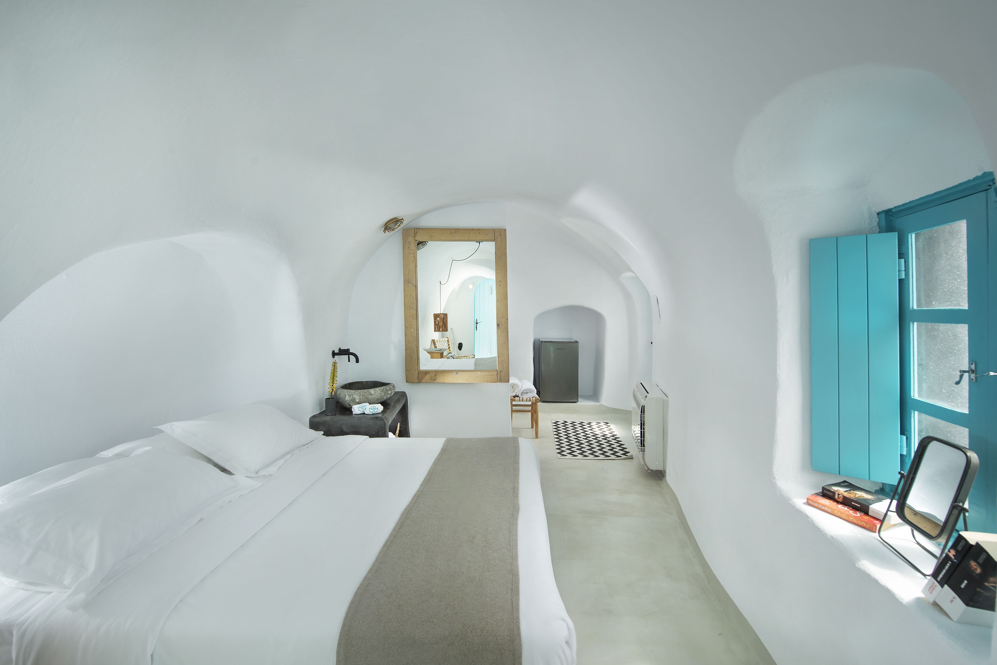 Una stanza con un letto, un tavolino, una sedia e una porta con vetri satinati.