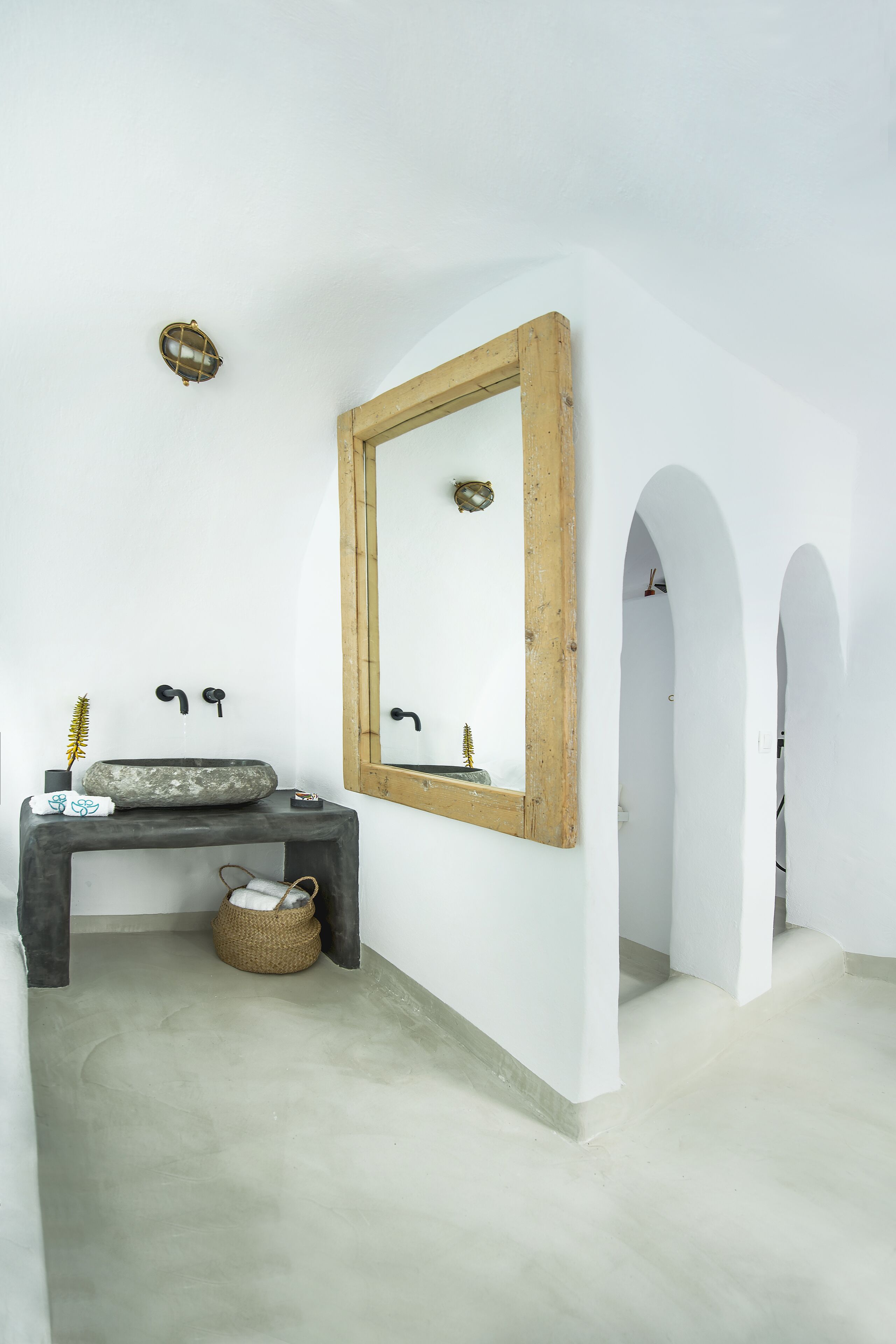 A bathroom with a stone sink, wooden-framed mirror, and a small basket.