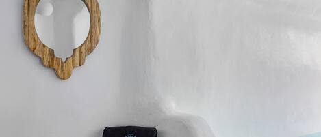 A minimalist room with a wooden-framed mirror, a black bag with a logo, and a view of the sky.