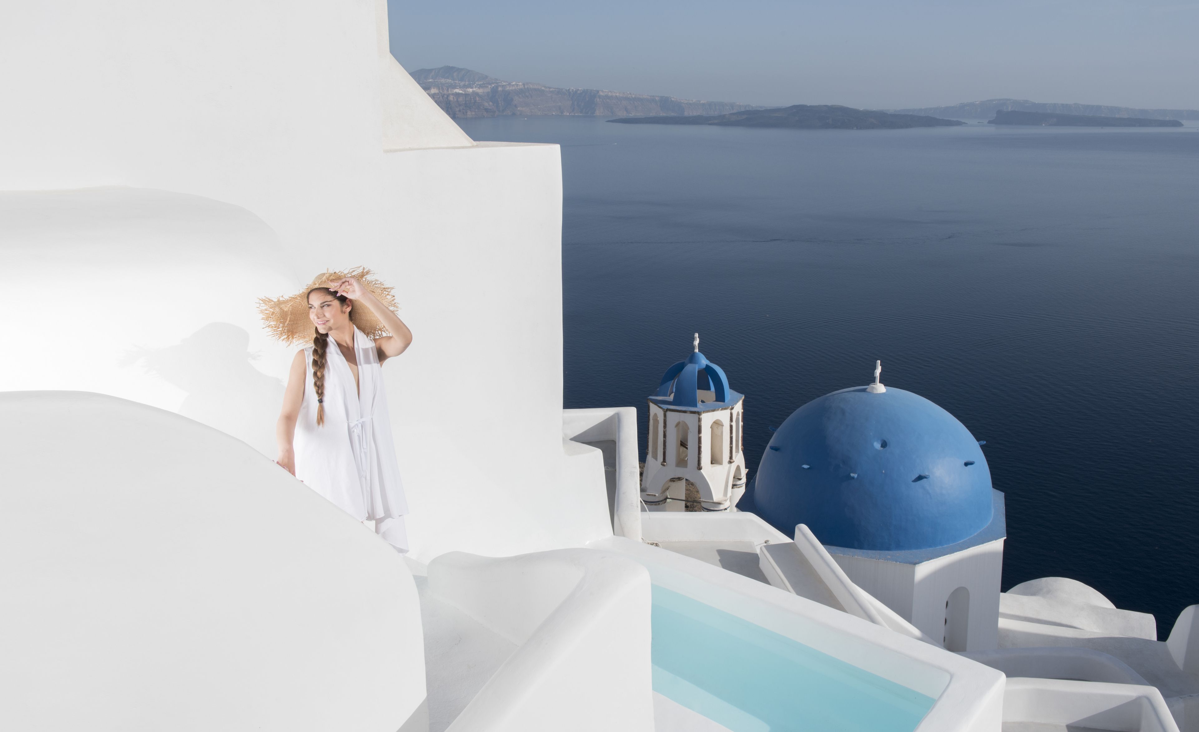Una persona in piedi su un edificio bianco con cupole blu, che guarda uno specchio d'acqua.