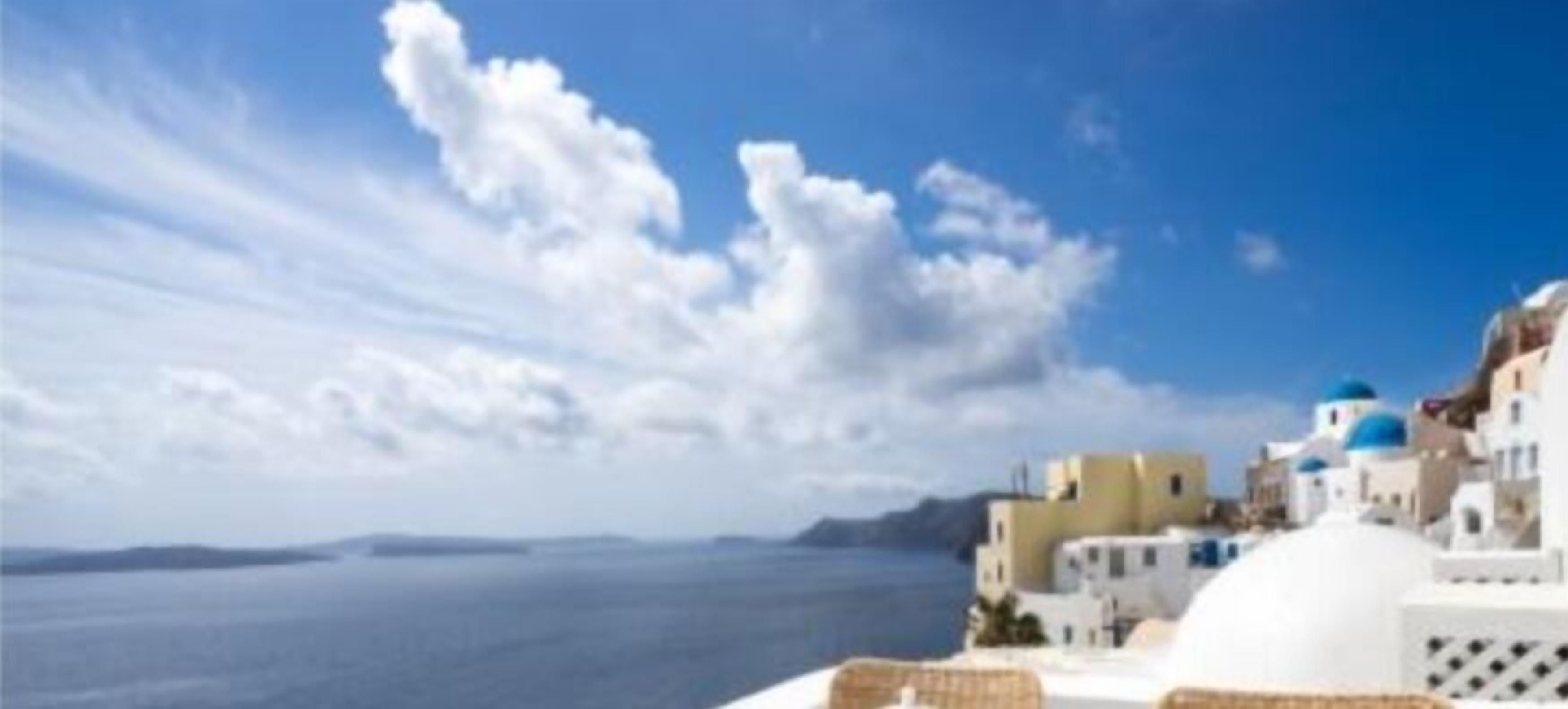A coastal view with white buildings and blue domes, likely a hotel or resort in a Mediterranean setting.