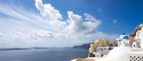 A coastal view with white buildings and blue domes, likely a hotel or resort in a Mediterranean setting.