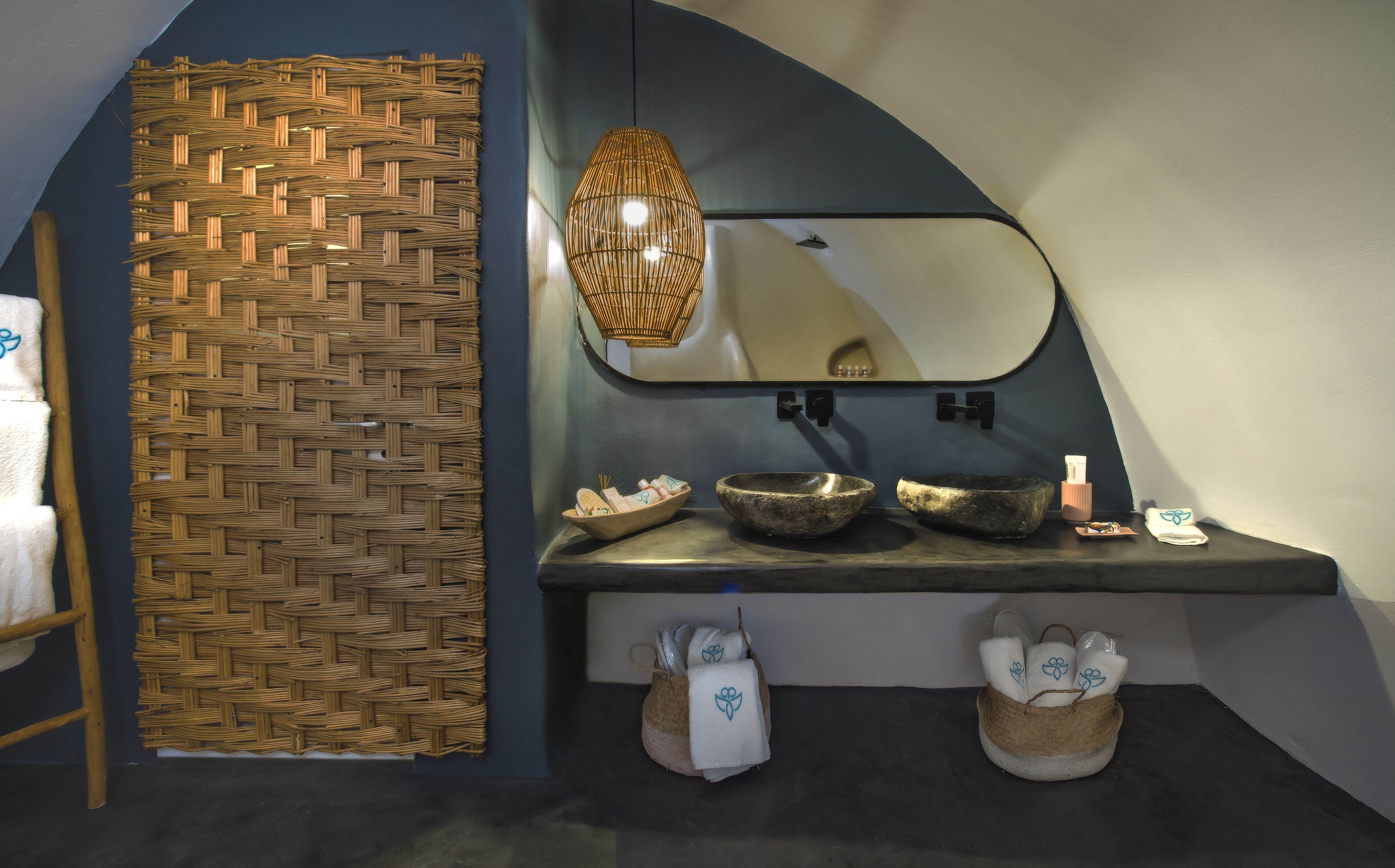 Un baño con pared de tejido, espejo, dos lavamanos de piedra y toallas.