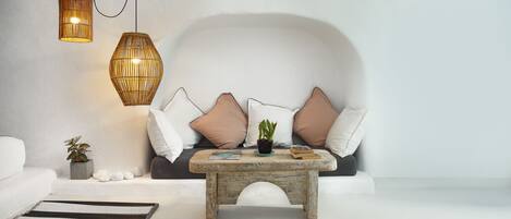 Una sala de estar moderna con un sofá blanco, una mesa de centro de madera y dos lámparas colgantes de mimbre.