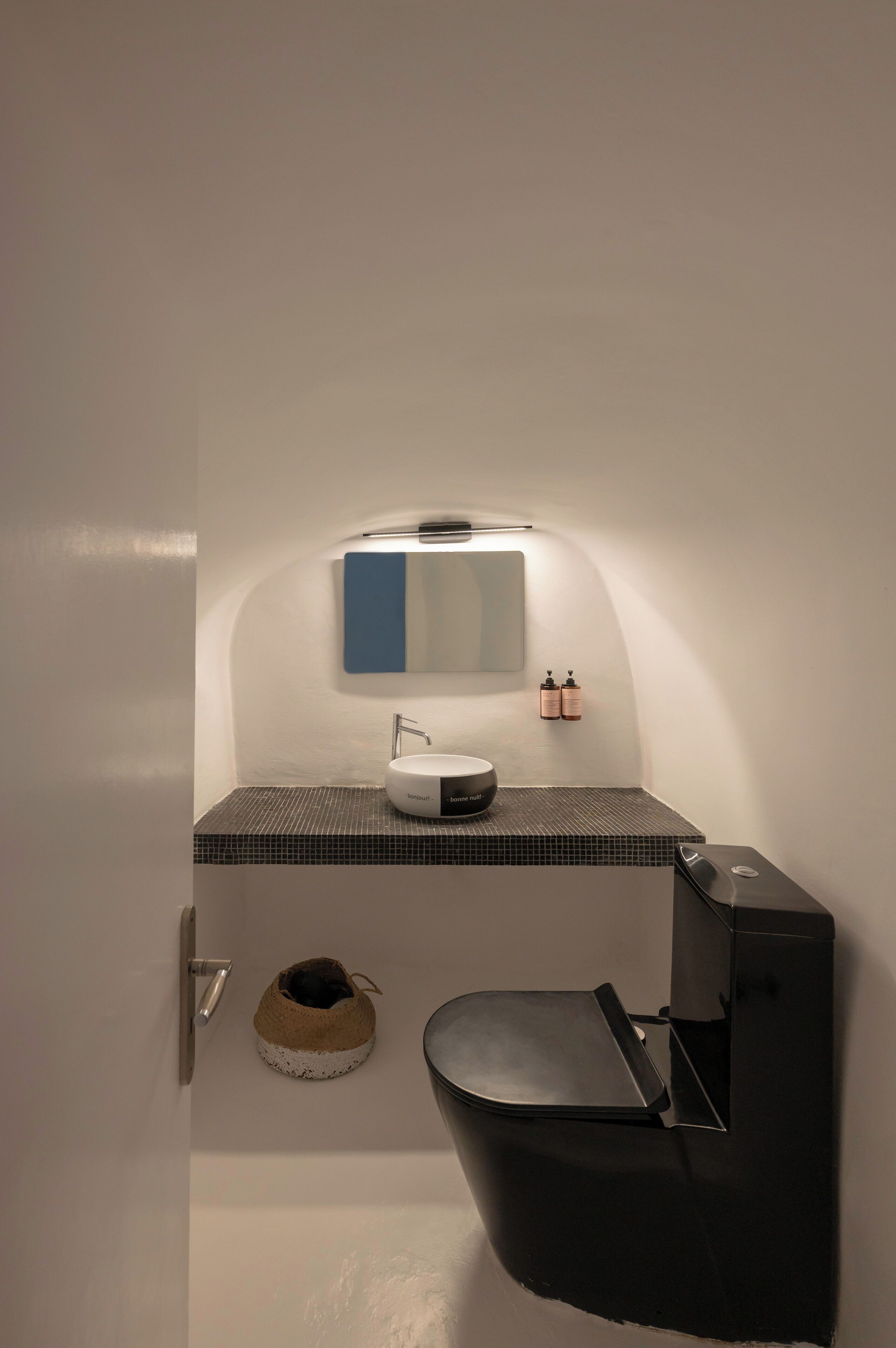 A compact bathroom with a white sink, a mirror, and a small toilet.